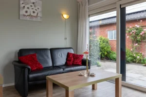 Zwarte bank met een bruine salontafel, waarop een bloemetje staat