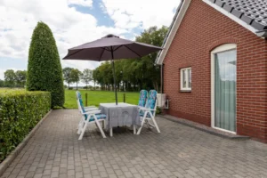 Zijaanzicht van het appartement, met een tuinset en parasol
