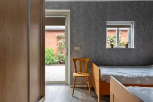 Slaapmaker met twee bedden uitkijkend op roze bloeiende bloemen.