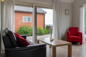 Lichte woonkamer met een zwarte bank en rode stoel