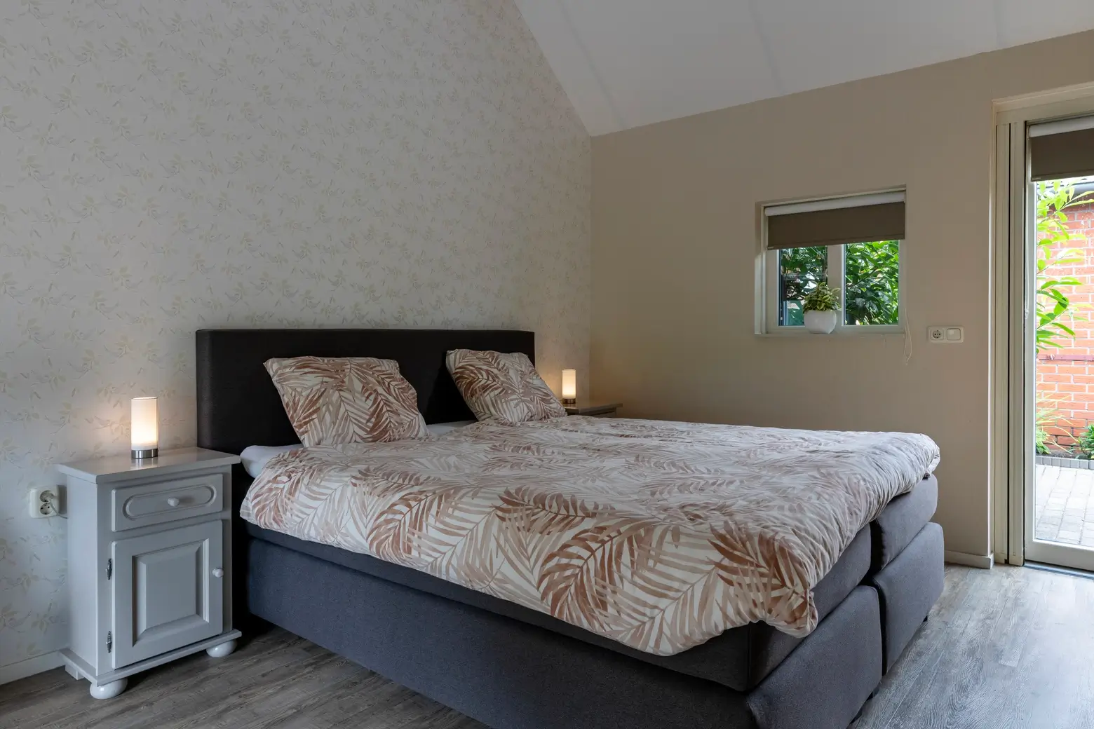 Hoofdslaapkamer met tweepersoons boxspring bed en nachtkastjes.