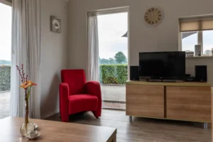 Een lichte zithoek met een rode stoel